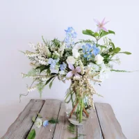 Berbagai macam bunga hias di dalam vas kaca transparan yang sama.