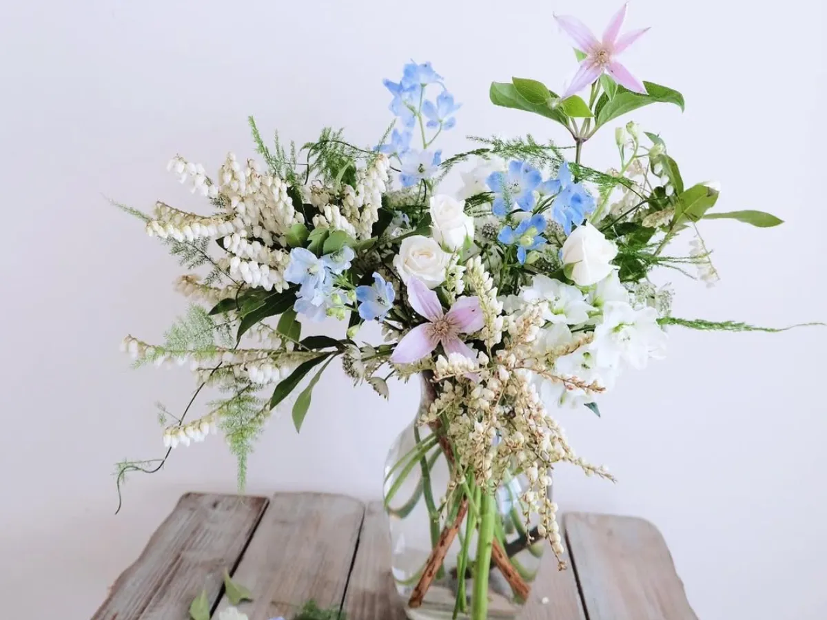 Berbagai macam bunga hias di dalam vas kaca transparan yang sama.